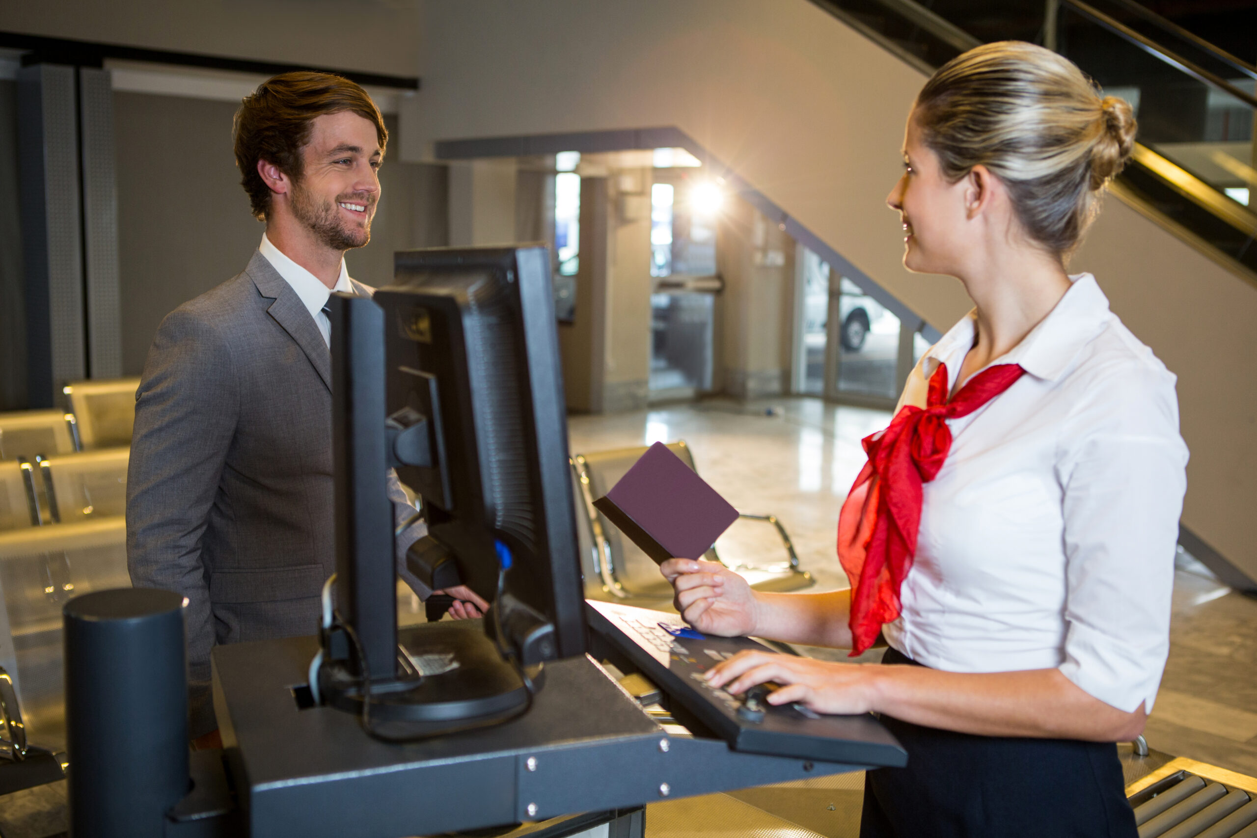 Businessman interacting with female airport staff at the check in desk in airport terminal