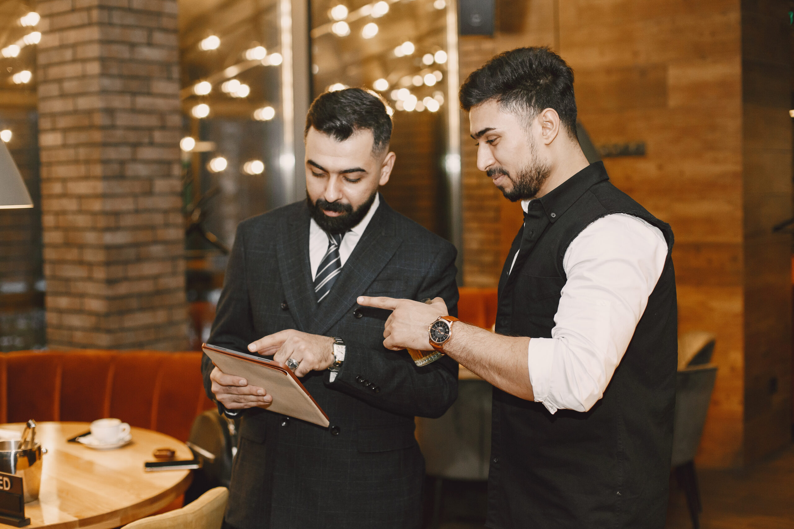 Handsome man in a black suit. Businessmen working in a cafe. People stands and looks in a documents.